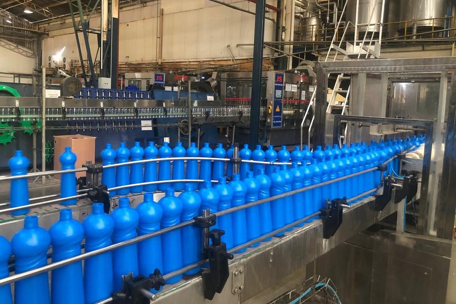 Linha de envase com frascos azuis em transporte na esteira